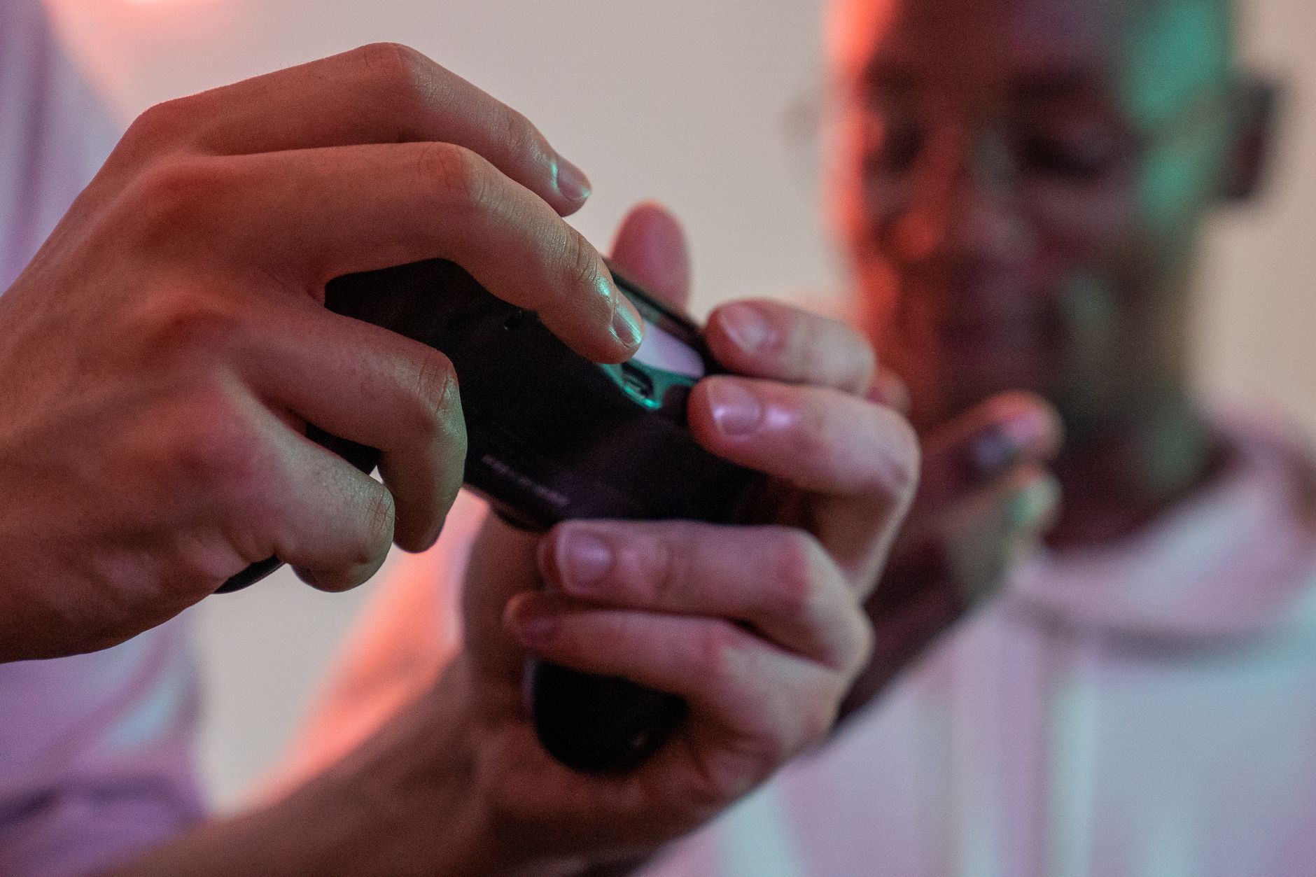 A close-up of two people intensely playing with a game controller, capturing gaming excitement.