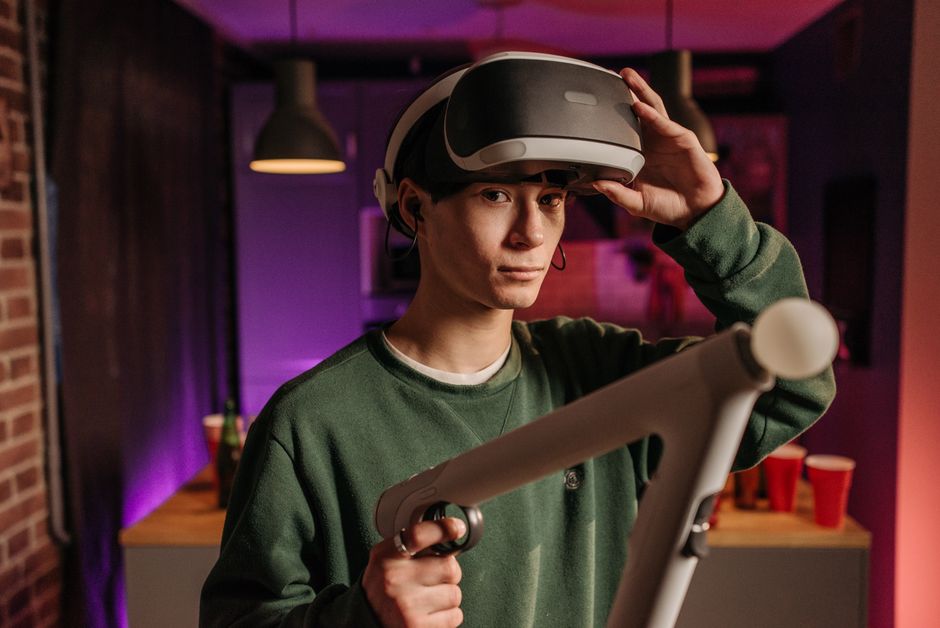 A young man explores virtual reality gaming with a headset and controllers in a cozy indoor setting.