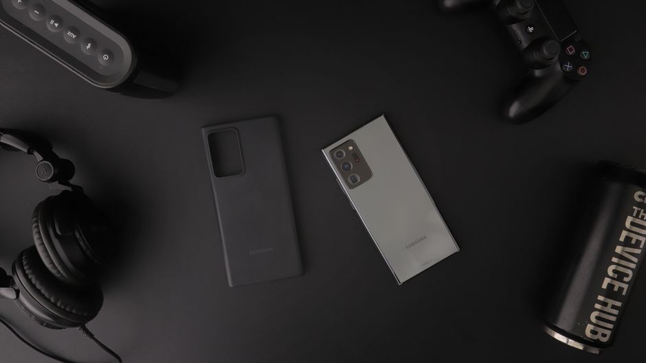 Flat lay of modern electronic gadgets including headphones, phone, and gaming controller on a table.