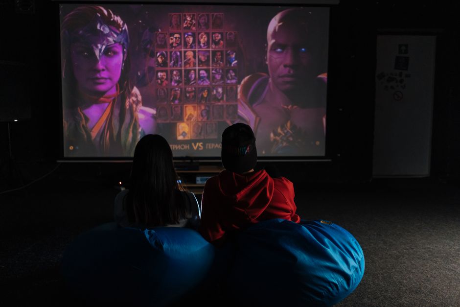 Two friends enjoying a video game session on a projector screen, immersed in gameplay.