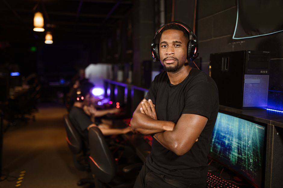 A serious young man with headphones in a gaming arena, conveying focus and determination.