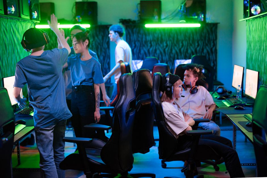 A diverse group of young gamers enjoying an energetic session in a vibrant esports arena, showcasing teamwork and excitement.
